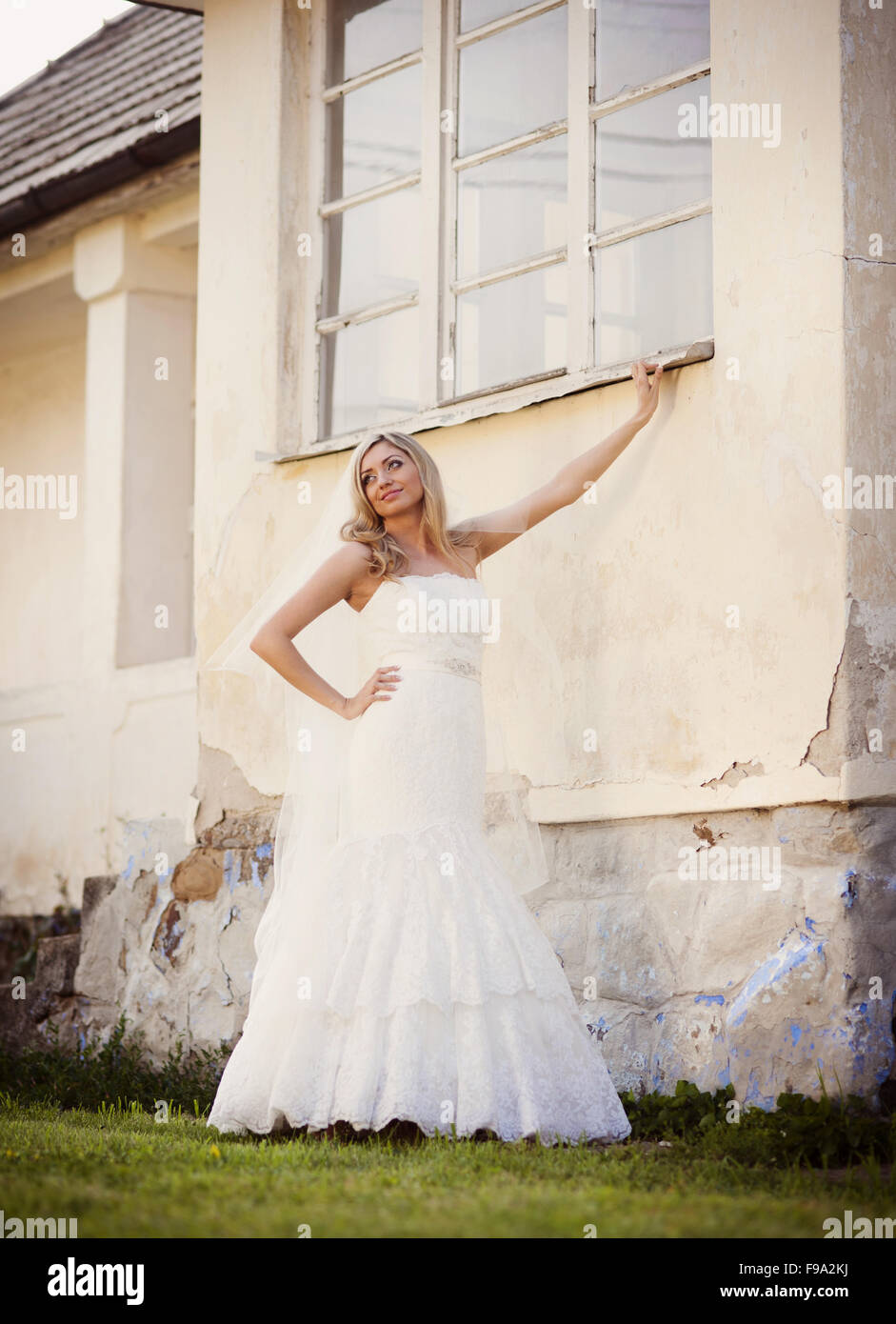 Schöne junge blonde Braut posiert von alten Haus Stockfoto