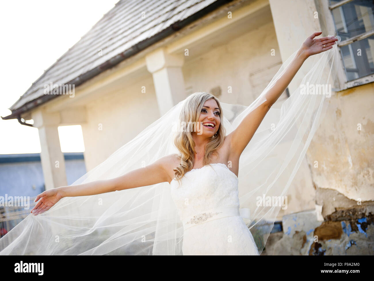Schöne junge blonde Braut mit Schleier von alten Haus posiert Stockfoto
