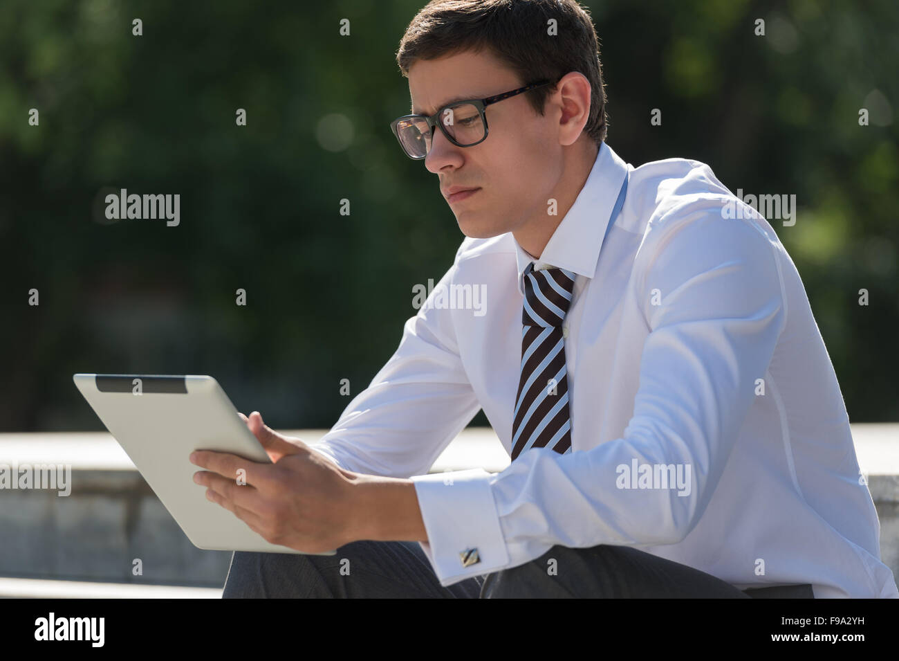 Junger Mann im Freien im Park mit Tablet-PC Stockfoto