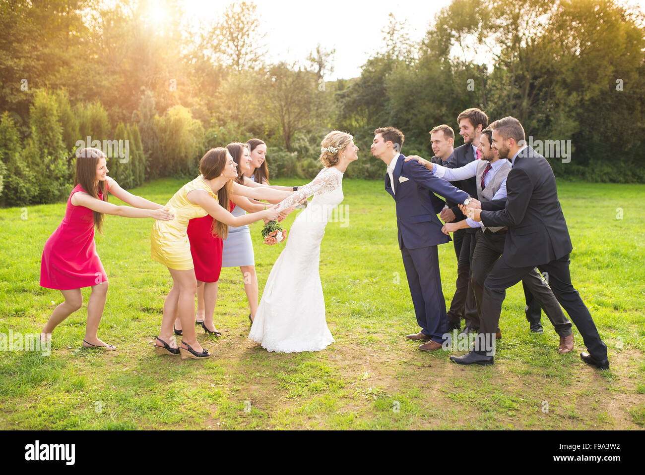 Lustige Porträt des frisch verheirateten Paar küssen, Brautjungfern und Trauzeugen in sonnigen, grünen Park Anfahren Stockfoto