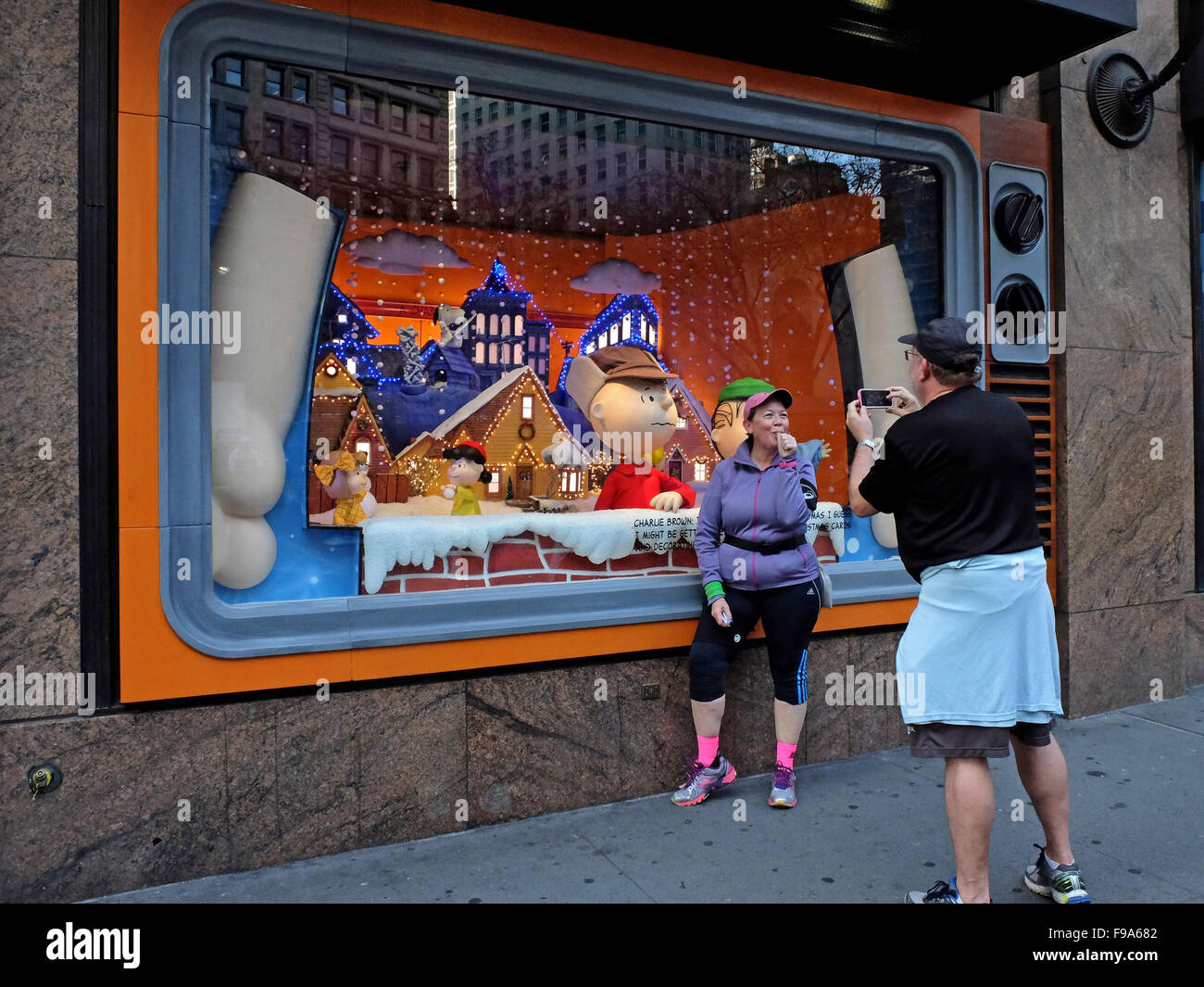 Touristen-Pose für ein lustiges Foto vor a Charlie Brown Christmas Fenster bei Macy's Herald Square, New York City. Stockfoto