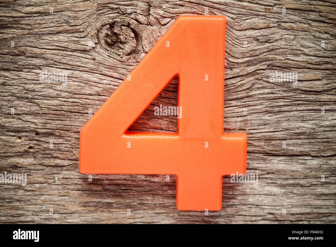 Orange Nummer vier auf dem hölzernen Hintergrund Stockfoto