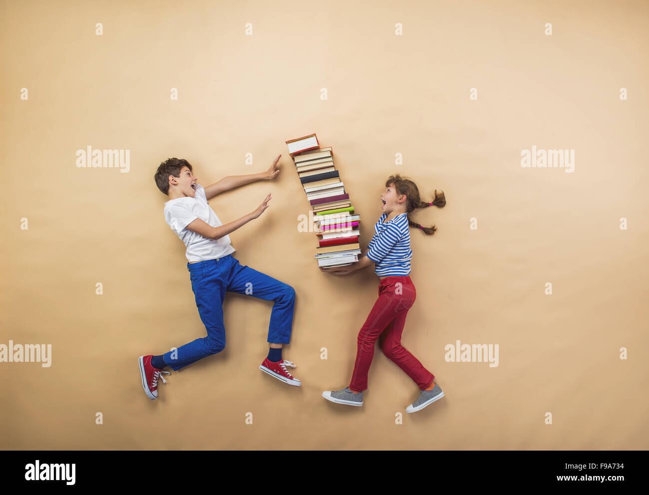 Glückliche Kinder, die spielen mit Gruppe von Büchern im studio Stockfoto