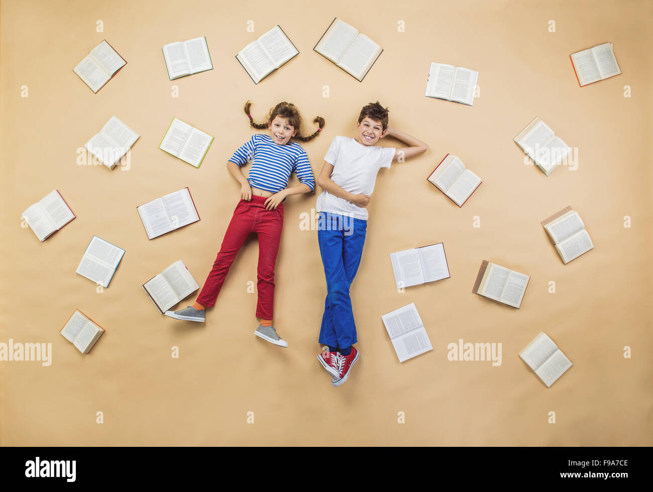 Glückliche Kinder auf dem Boden liegend mit Gruppe Bücher Stockfoto