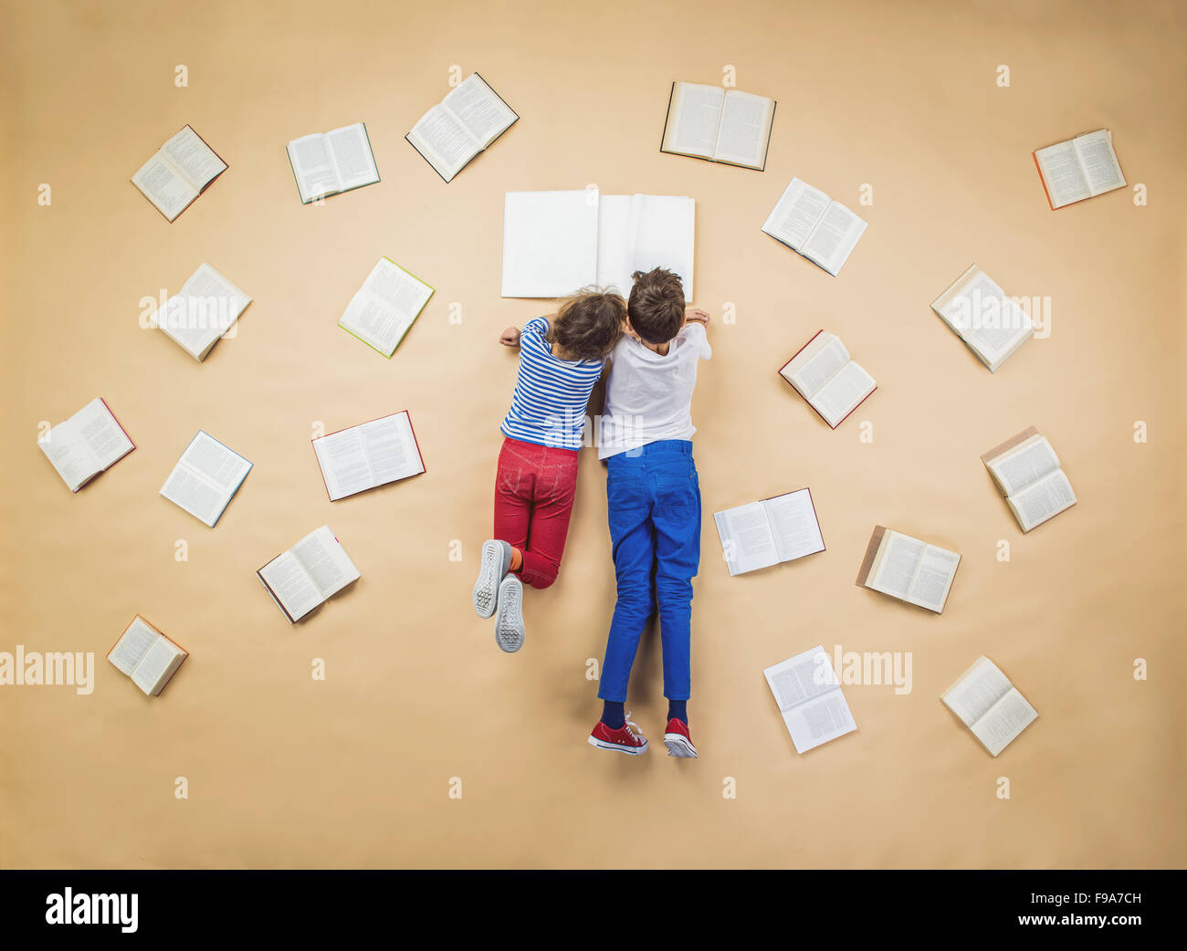 Glückliche Kinder sind auf dem Boden mit Gruppe Bücher um sie herum Buch Stockfoto