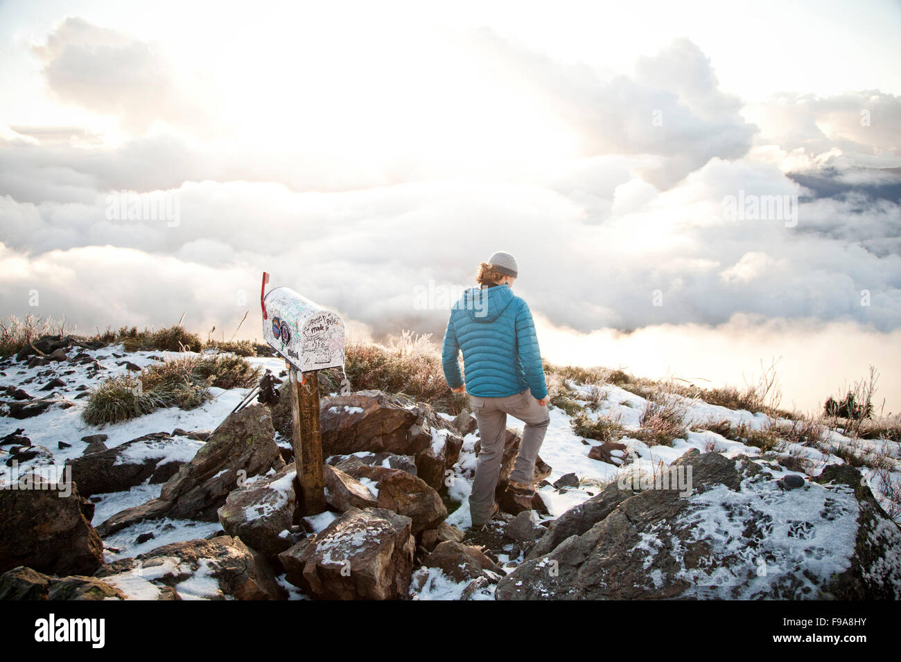 POSTFACH PEAK, NORTH BEND, WASHINGTON, USA. Eine junge Frau in eine Krickente Daunenjacke Wanderungen zwischen schneebedeckten Felsen und in der Nähe ein Postfach an der Spitze eines Berges. Stockfoto
