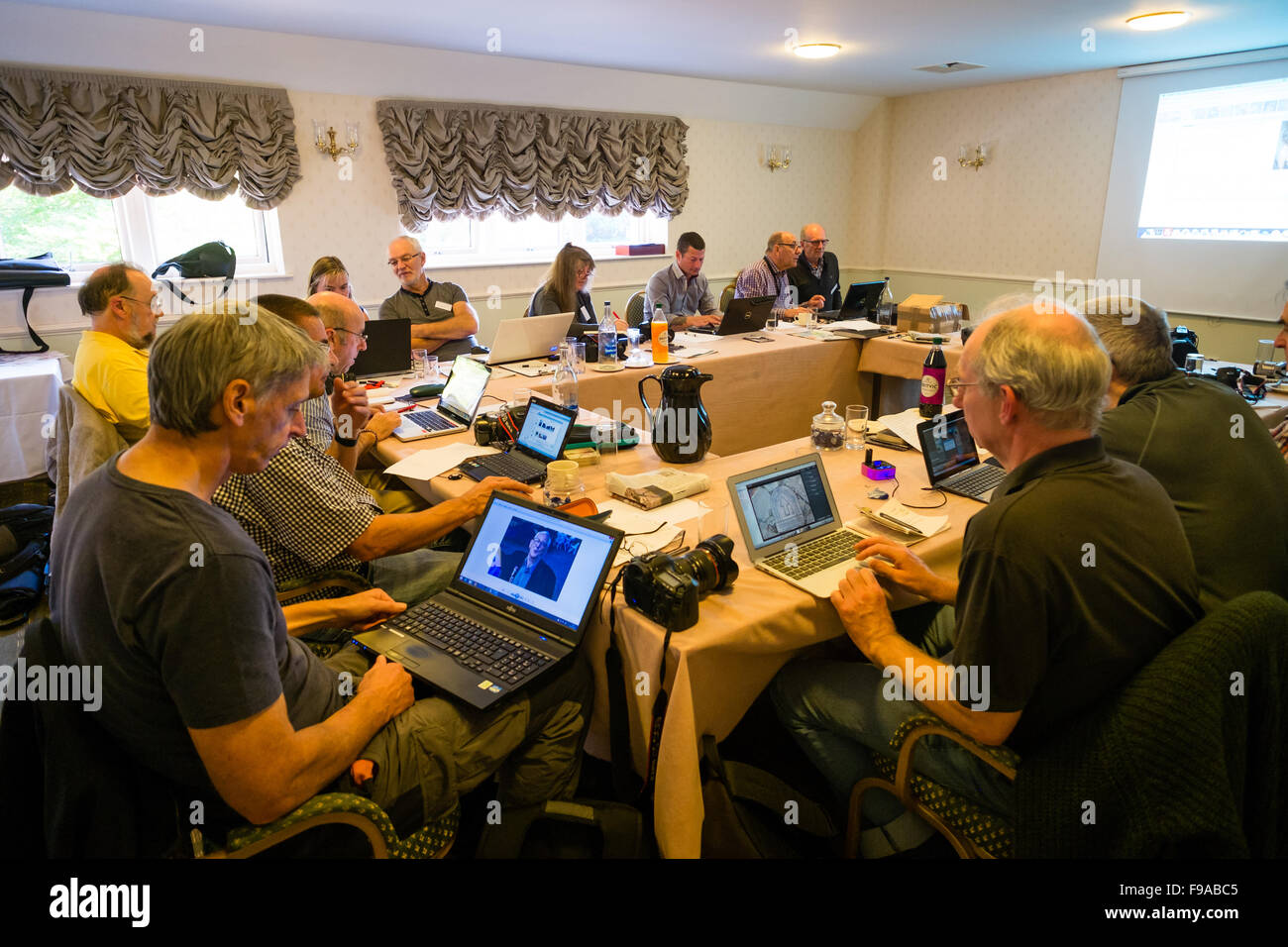 Eine Gruppe von Fotografen ein Tabellenbearbeitung herumsitzen und Bearbeitung ihrer Digitalfotos (hergestellt in der kleinen englischen Marktstadt von Cirencester) auf Laptop-Computern in einem Hotelzimmer treffen während einer eintägigen Workshop Klasse Lektion Seminar Tutorial auf Alamy Materialbibliothek Fotografie UK Stockfoto