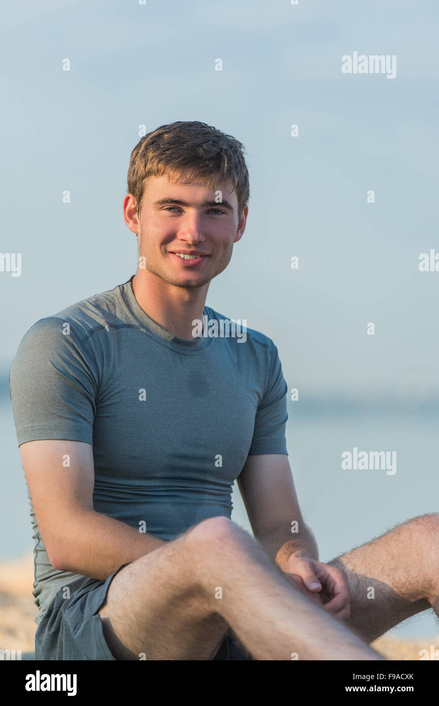 Sportlichen Mann ruht nach dem Training am Strand bei Sonnenuntergang Stockfoto