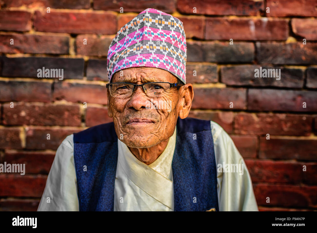 Älterer Mann mit Brille sitzt auf der Straße von Kathmandu Stockfoto
