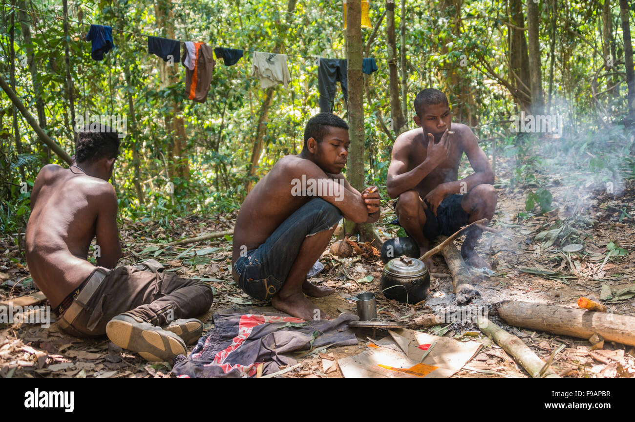 Drei junge Eingeborene Orang Asil Männer sitzen auf dem Boden in den Dschungel, Rauchen, Naturvolk, tropischer Regenwald Stockfoto