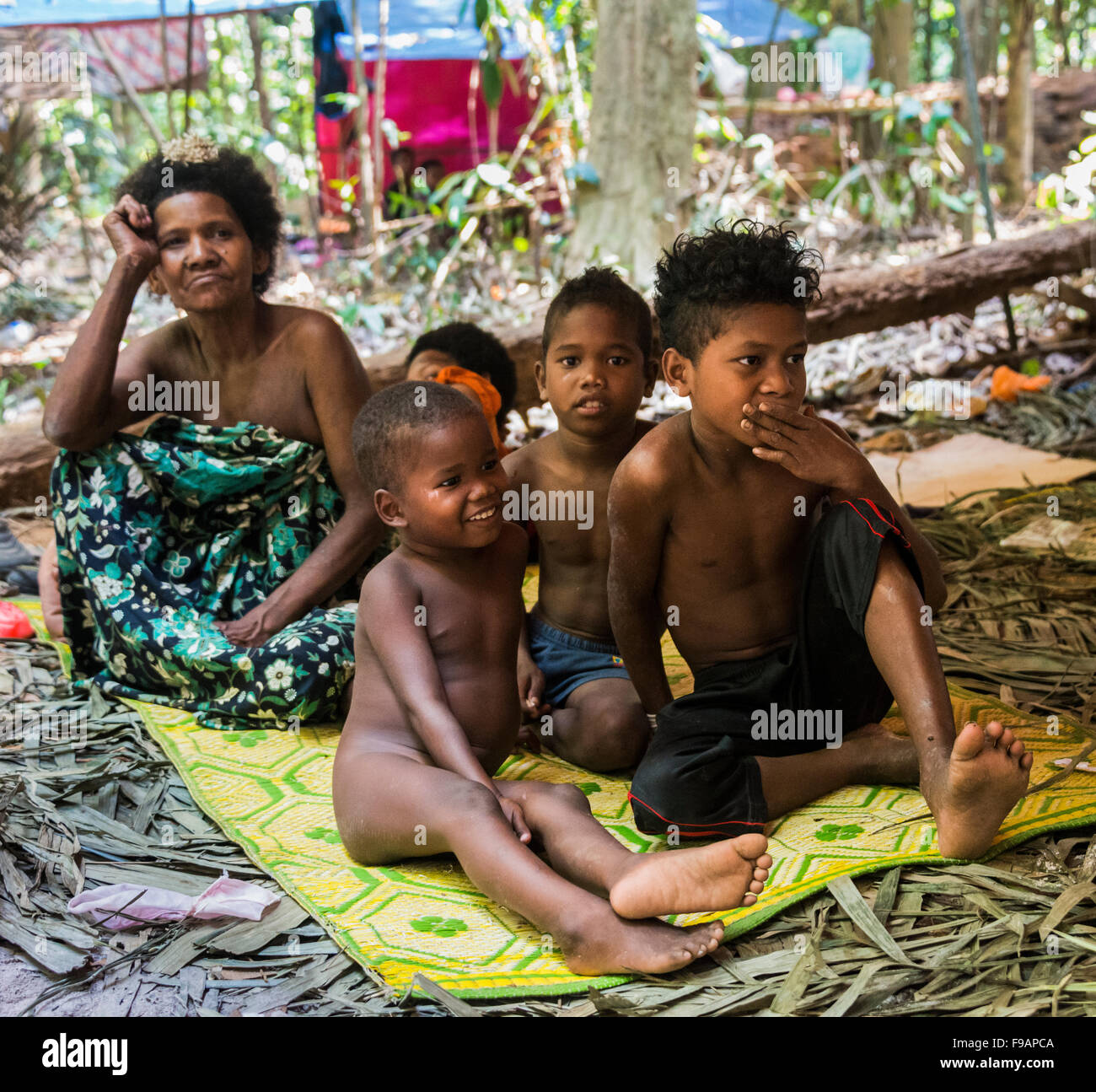 Frau und Kinder, Eingeborene Orang Asil, sitzen auf dem Boden im Dschungel, indigene Völker, tropischer Regenwald Stockfoto