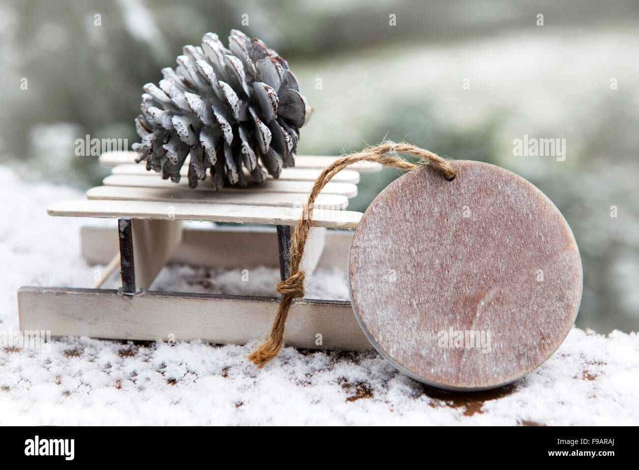 Miniatur aus Holz Schlitten mit Tannenzapfen und hölzernen Tag im Schnee Stockfoto