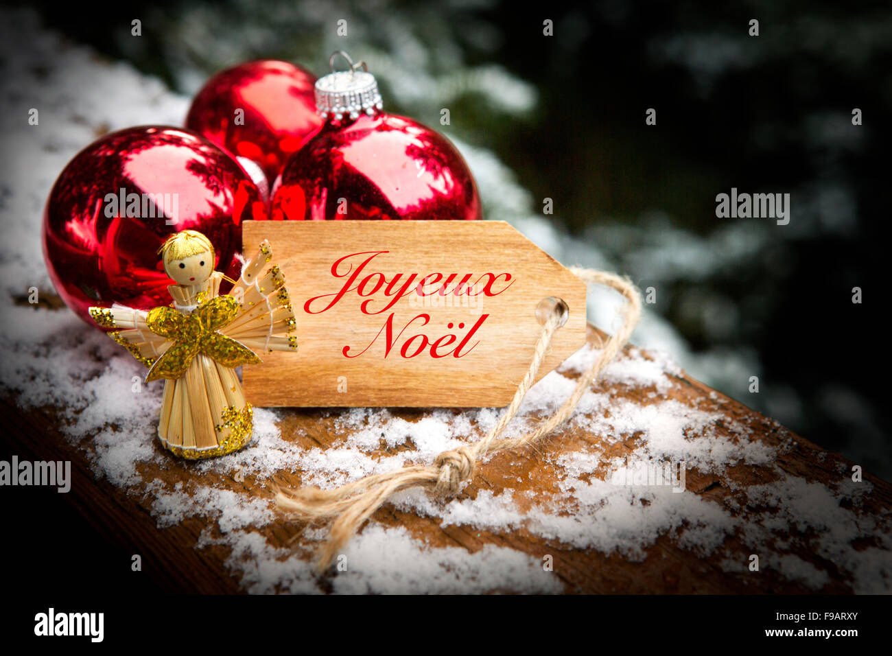 Holz-Tag mit dem französischen Wort "Joyeux Noel" (Frohe Weihnachten) neben Weihnachtskugeln und Engel Stockfoto