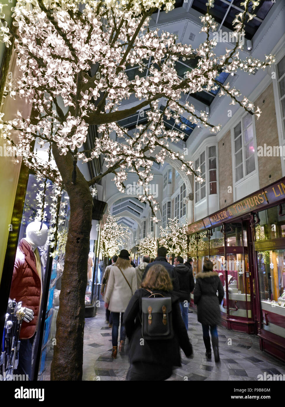 Burlington Arcade in Piccadilly mit traditionellen Weihnachtsschmuck und Shopper mit Einkaufstüten London UK beschäftigt Stockfoto