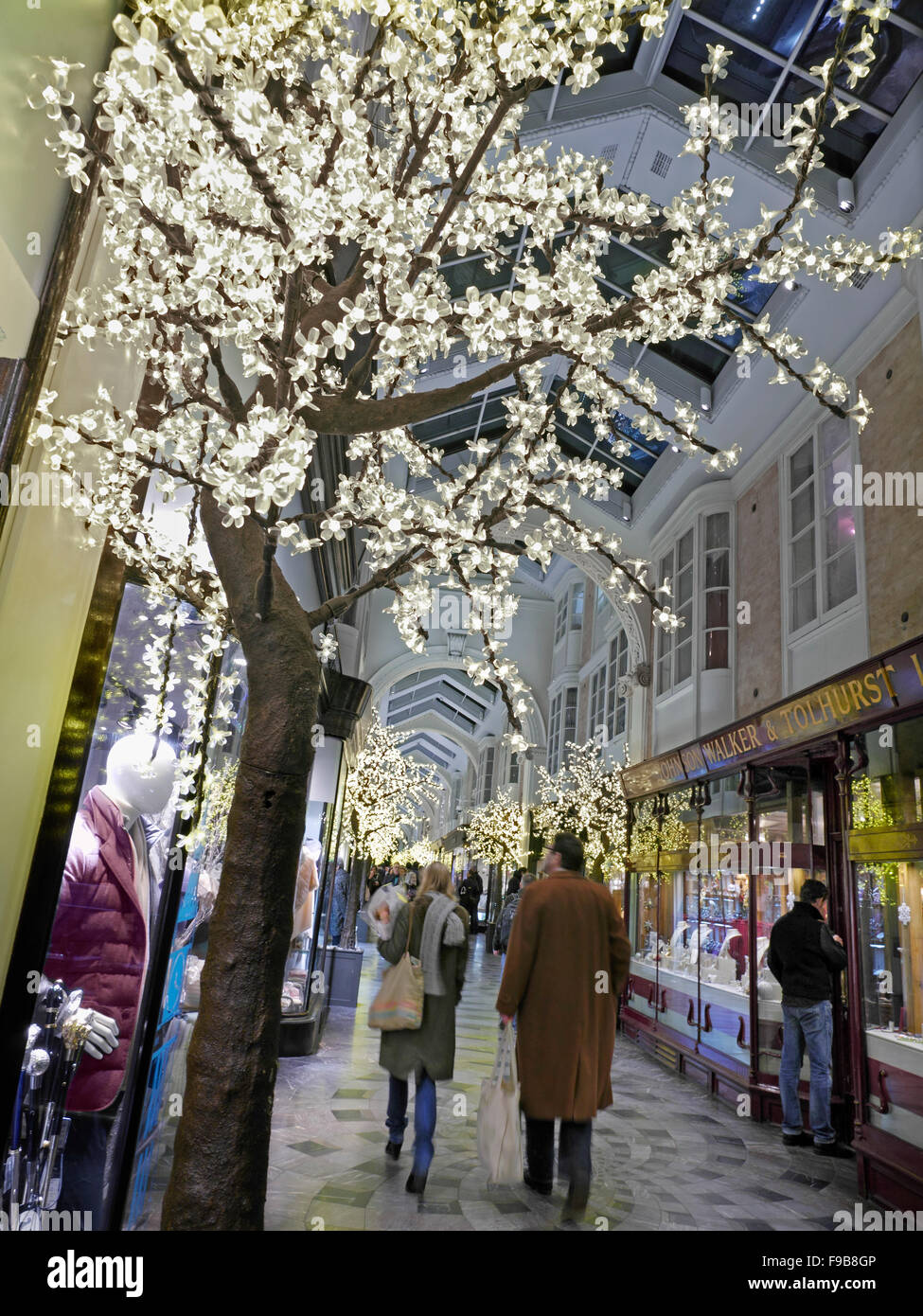 Burlington Arcade in Piccadilly mit beleuchteten Weihnachtsschmuck und Shopper mit Einkaufstüten London UK beschäftigt Stockfoto