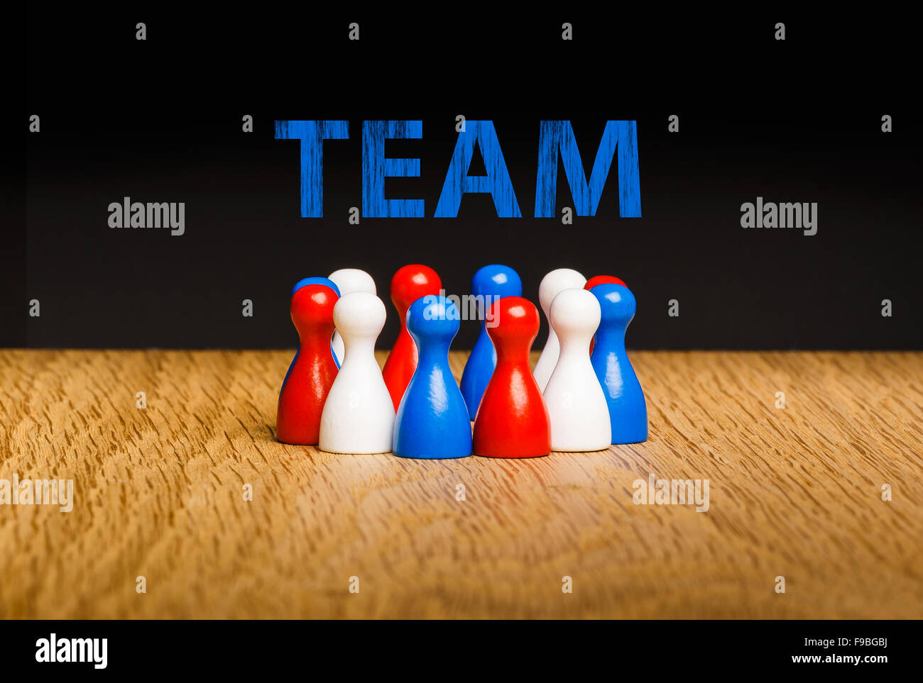 Konzept für Team, Teamarbeit mit blauer Kreide Text. Rote weiße blaue Bauer Figuren und schwarzem Hintergrund auf Eiche. Stockfoto
