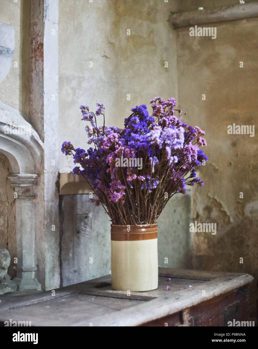 Steingut-Vase mit lila und Umzug getrocknete Blumen in einer Kirche oder Kapelle Stockfoto