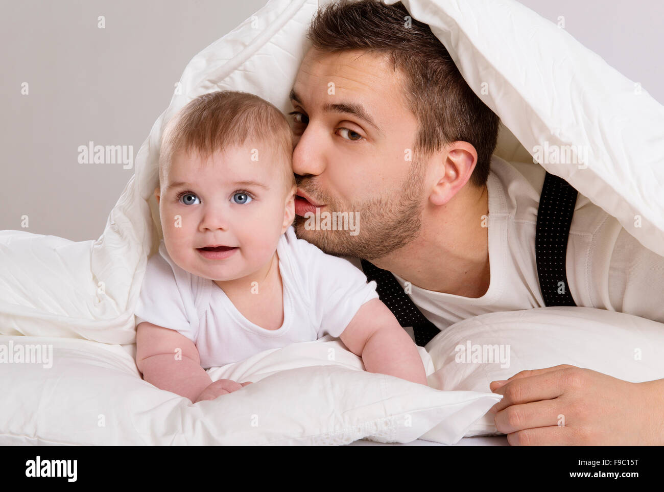 Junger Vater spielt mit Baby im Bett Stockfoto