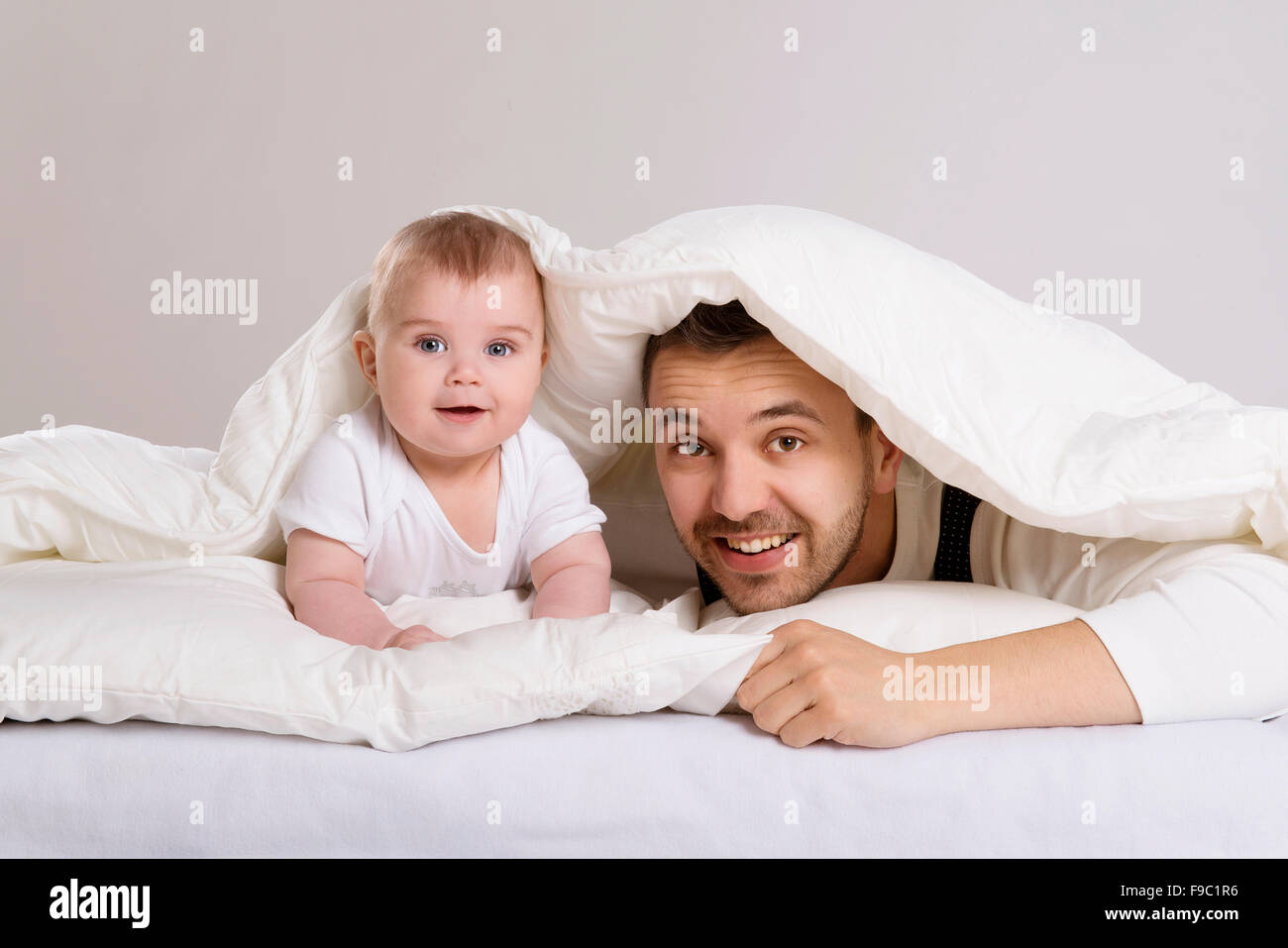 Junger Vater spielt mit Baby im Bett Stockfoto