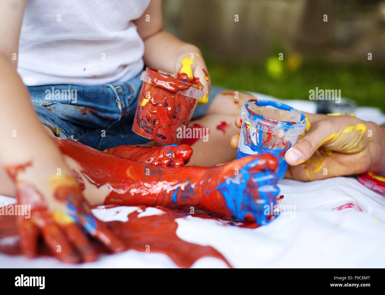 Nettes Kind malen mit lebendigen Farben im Garten Stockfoto