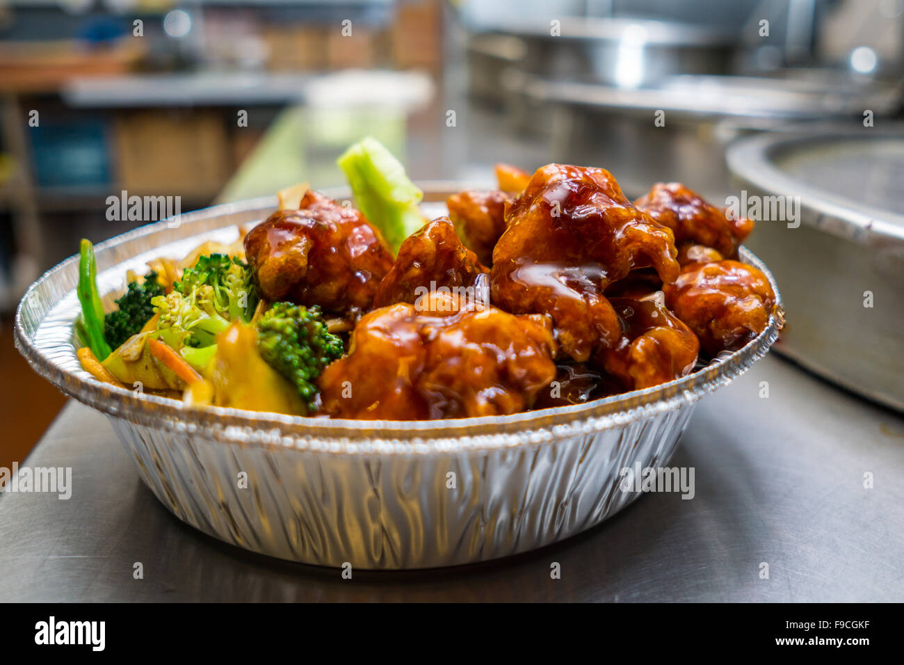 Beliebte chinesische Gericht allgemeine Tsos Hühnchen auf dem Küchentisch in einer Folie Container Stockfoto