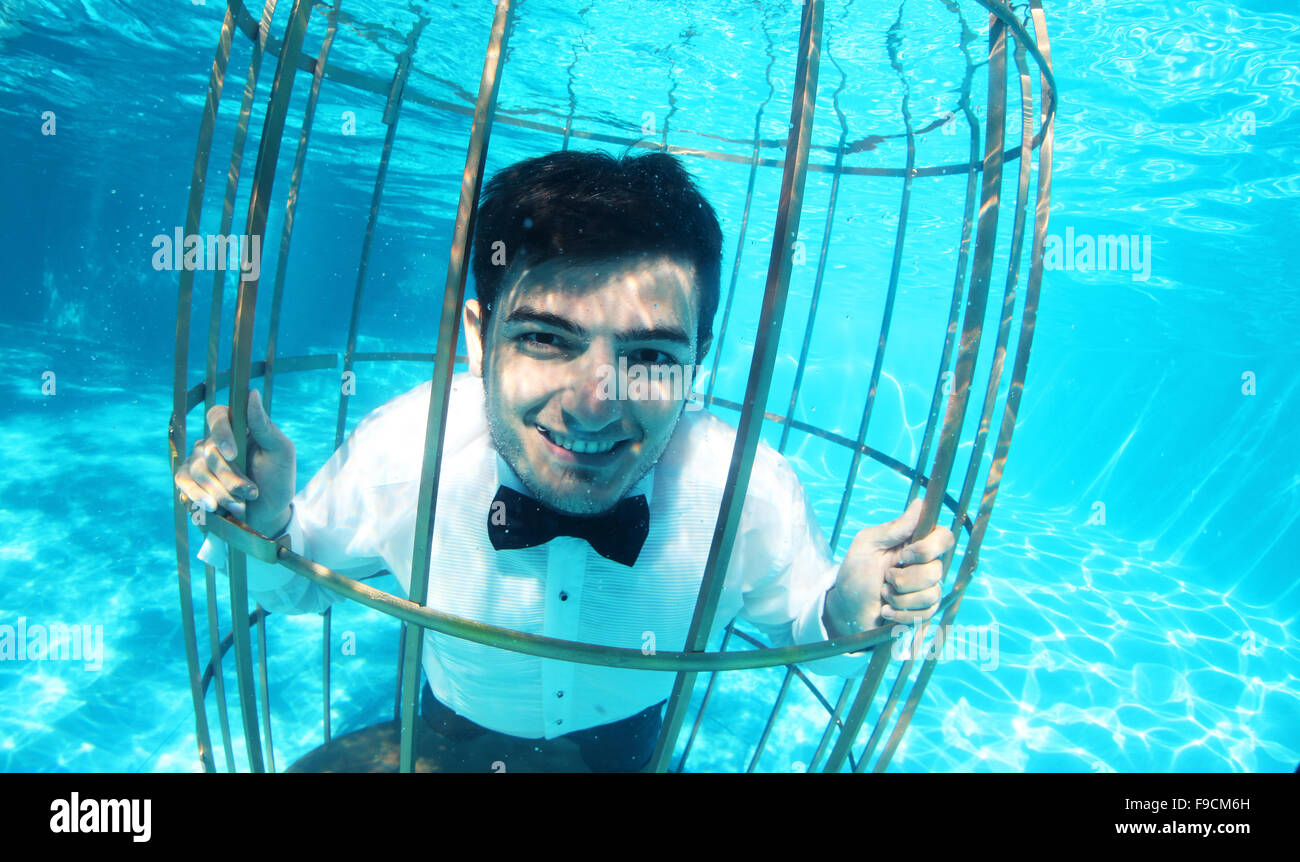 Lustige Bräutigam unter Wasser in einem Vogelkäfig Stockfoto