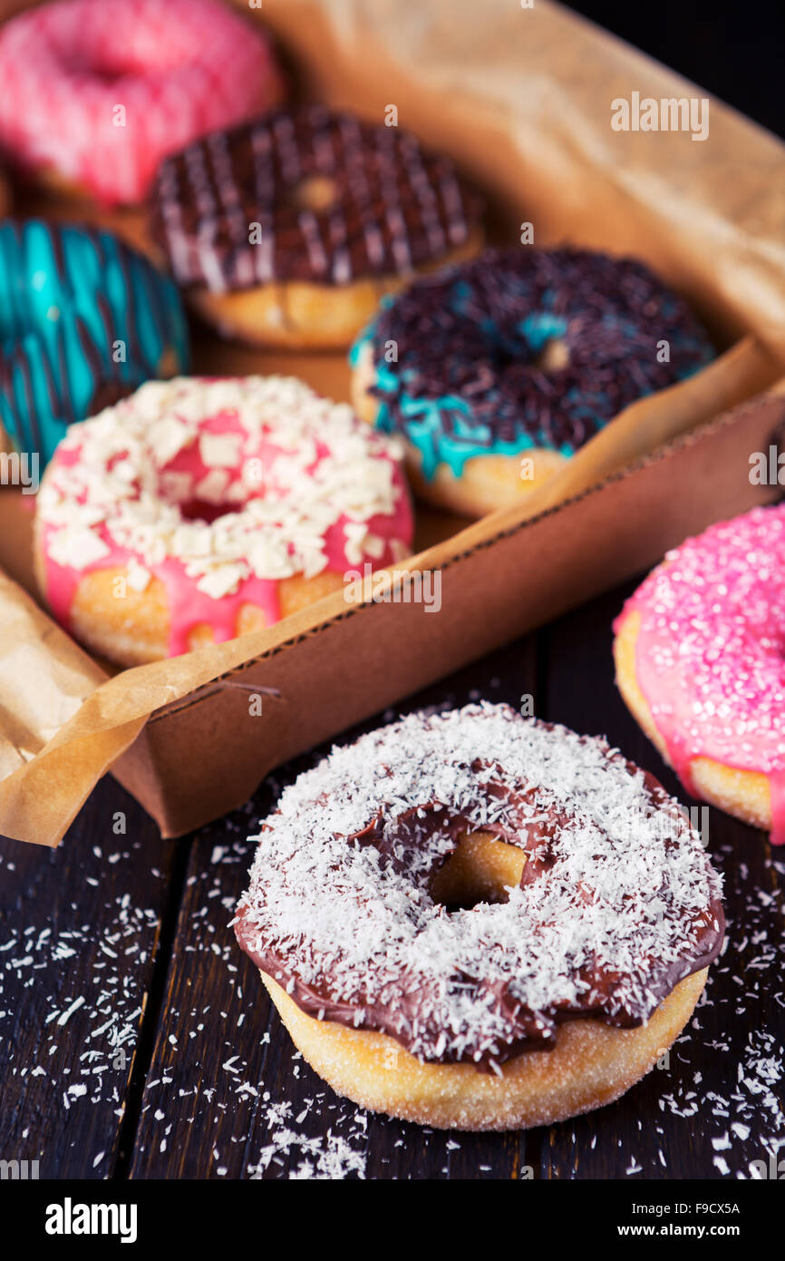 Eine Box mit frischen hausgemachten Donuts mit verschiedenen Belägen. Stockfoto