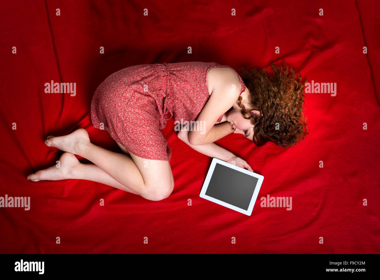 Schöne traurige Frau liegt auf rote Decke mit tablet Stockfoto
