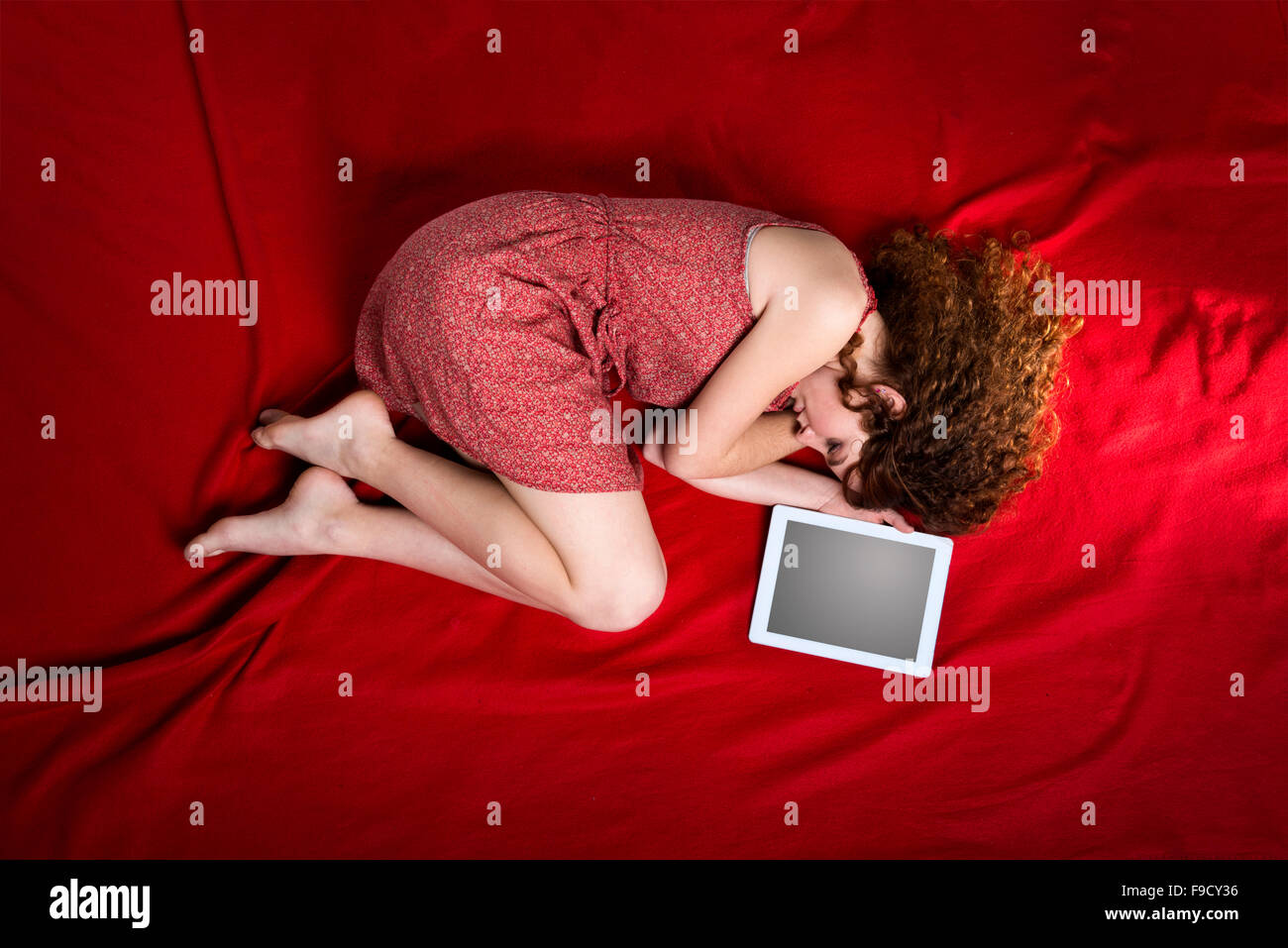 Schöne traurige Frau liegt auf rote Decke mit tablet Stockfoto