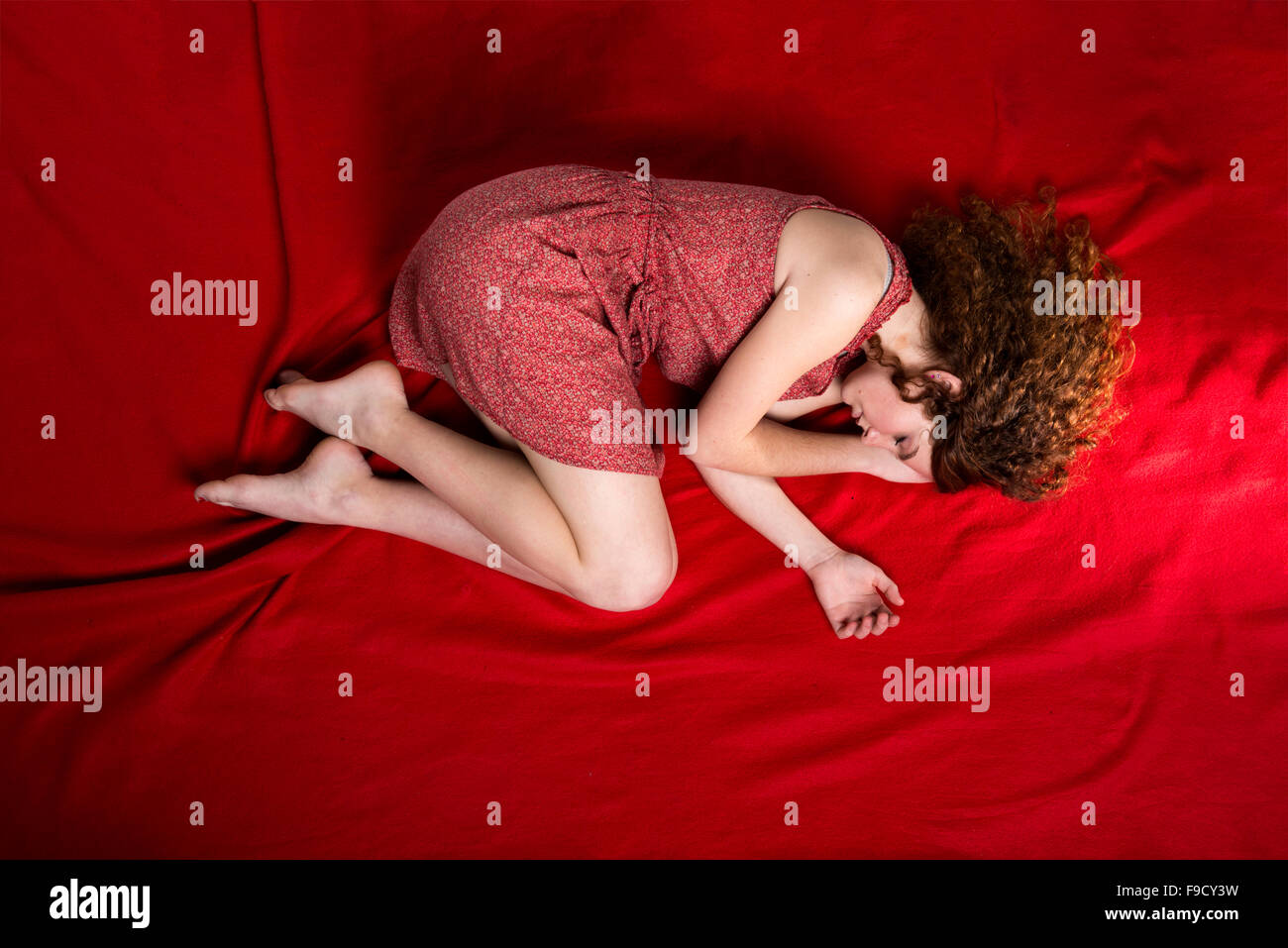 Schöne traurige Frau liegt auf rote Decke Stockfoto