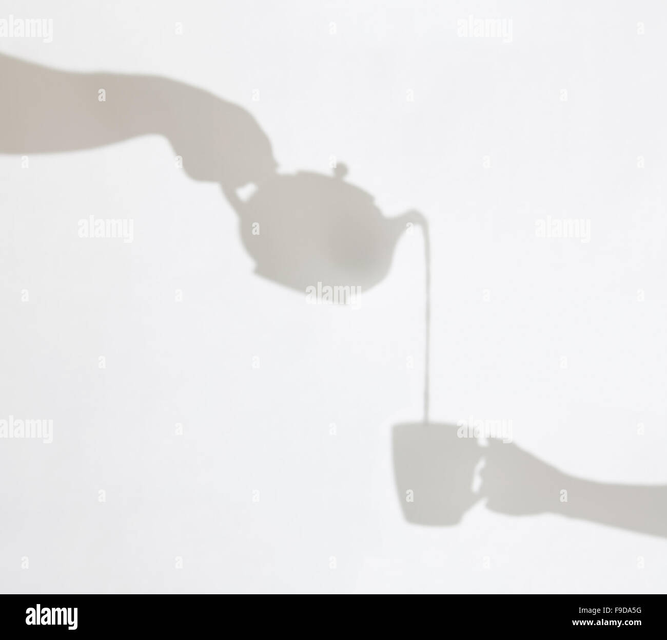 Zarte Schatten der Teekanne Gießen Flüssigkeit in eine Tasse von weiblichen Hand gehalten. Schattenspiel. Stockfoto