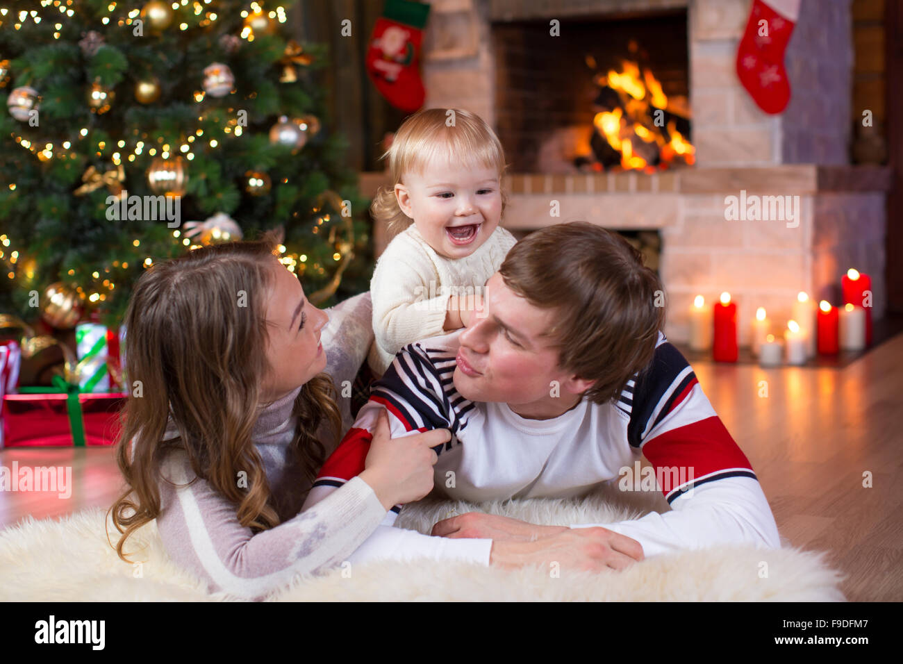 Glückliche junge Eltern und Kind viel Spaß in der Nähe von Weihnachtsbaum zu Hause.  Vater, Mutter und Sohn gemeinsam feiern Neujahr Stockfoto