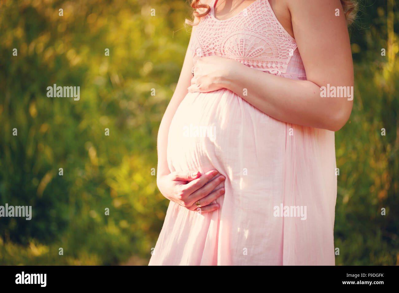 Schöne schwangere in rosa Kleid im Sommertag Stockfoto