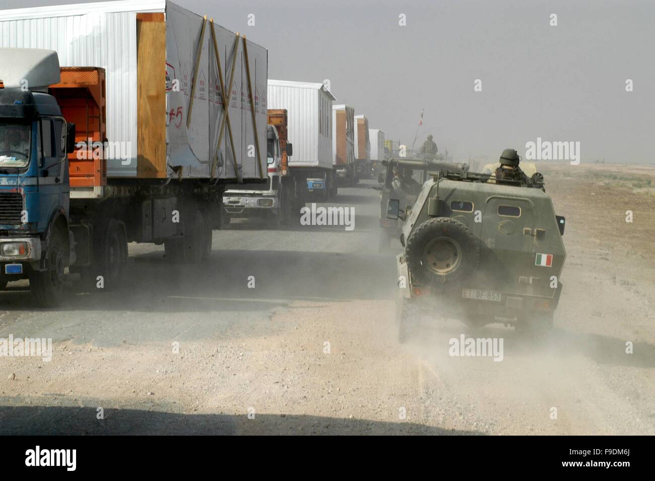 Italienische militärische Intervention im Irak (10/2004), italienische gepanzerte Fahrzeuge Begegnung eine Wiedereinlagerungsgebühr US-LKW-Konvoi mit vorgefertigt Häuser Stockfoto