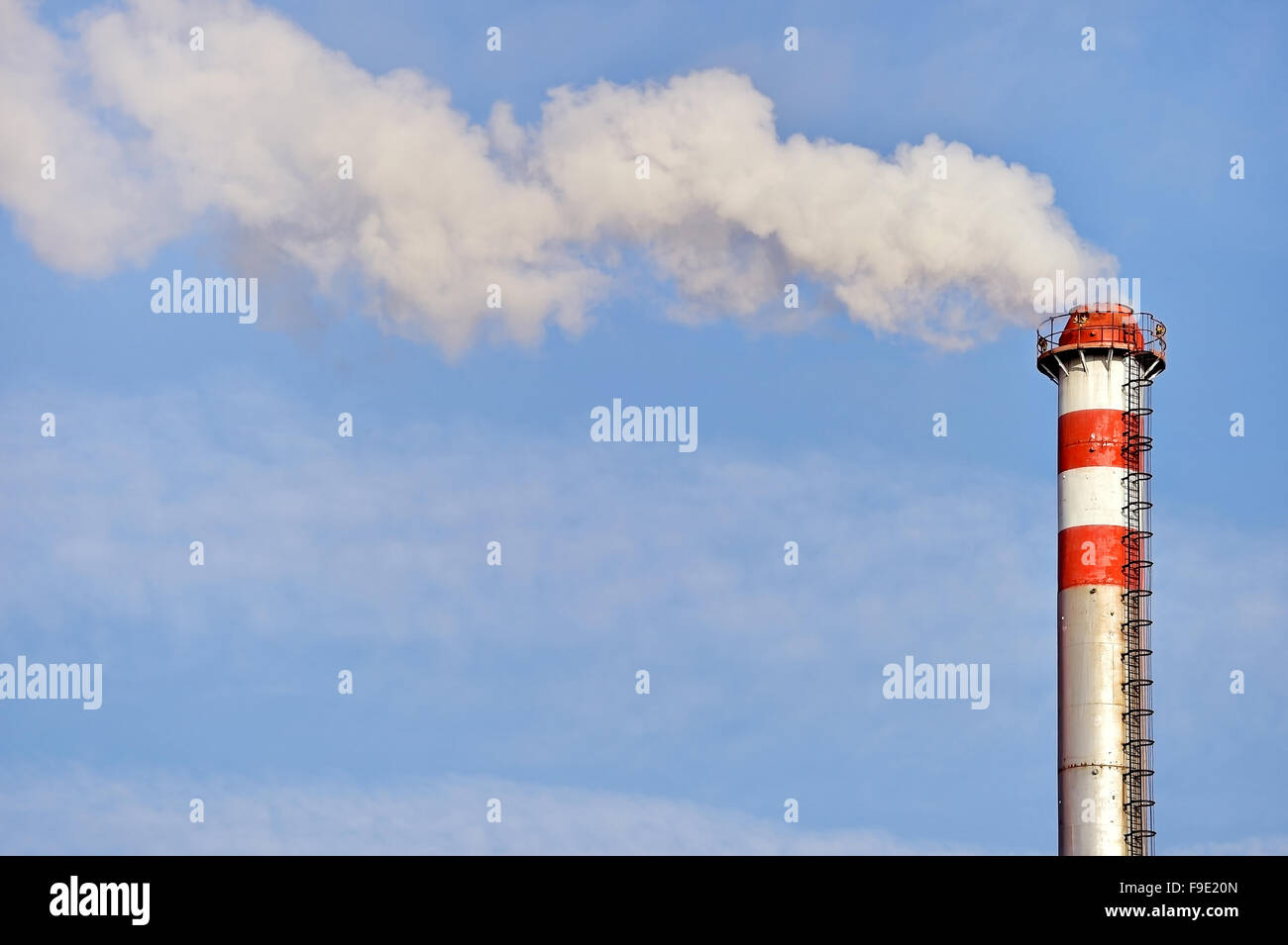 Rauch und Dampf, die sich aus einem petrochemischen Industrieanlagen Schornstein mit einem blauen Himmel im Hintergrund Stockfoto