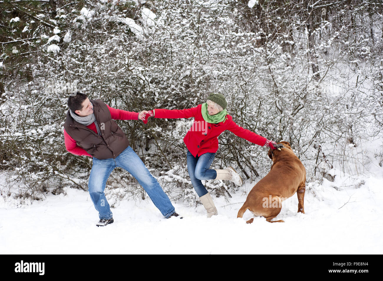 Frau und Mann haben Spaß mit Hund im verschneiten Winterlandschaft Stockfoto