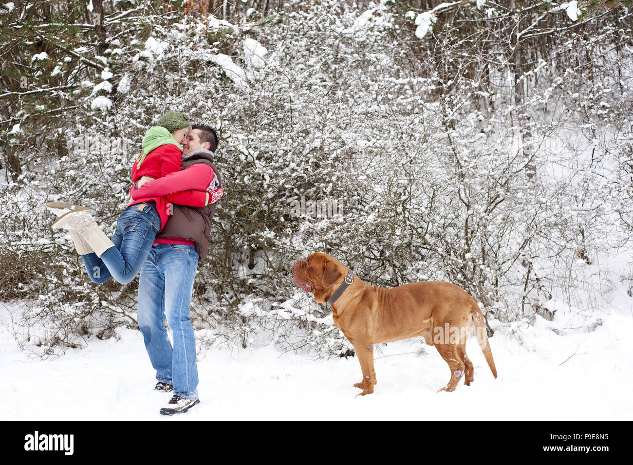 Frau und Mann haben Spaß mit Hund im verschneiten Winterlandschaft Stockfoto