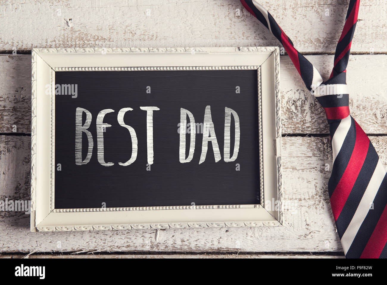 Rechteck-Bilderrahmen mit besten Papa Zeichen und bunte Krawatte auf Holzboden Hintergrund gelegt. Stockfoto