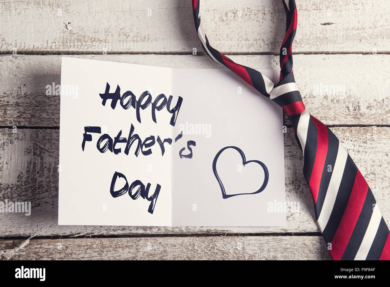 Glückliche Väter Tag Zeichen auf Papier und bunte Krawatte auf Holzboden Hintergrund gelegt. Stockfoto