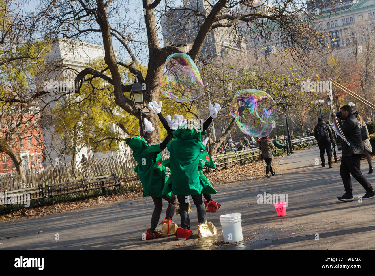 In Weihnachtskostüme gekleidete Männer jagen riesige Seifenblasen Washington Square, East Village, New York City, USA Stockfoto