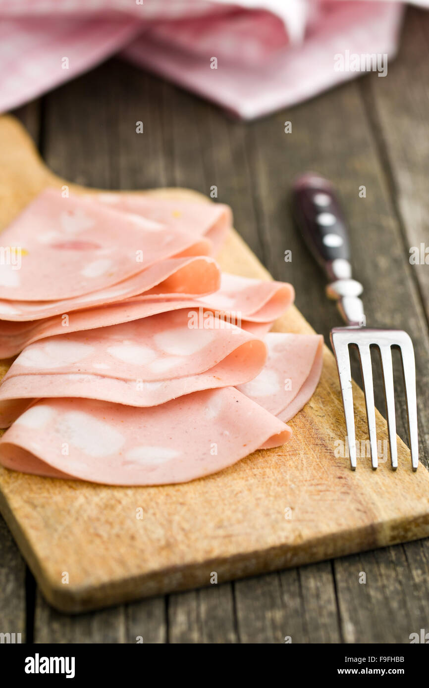 Scheiben Wurst Mortadella und Gabel auf Schneidebrett Stockfoto