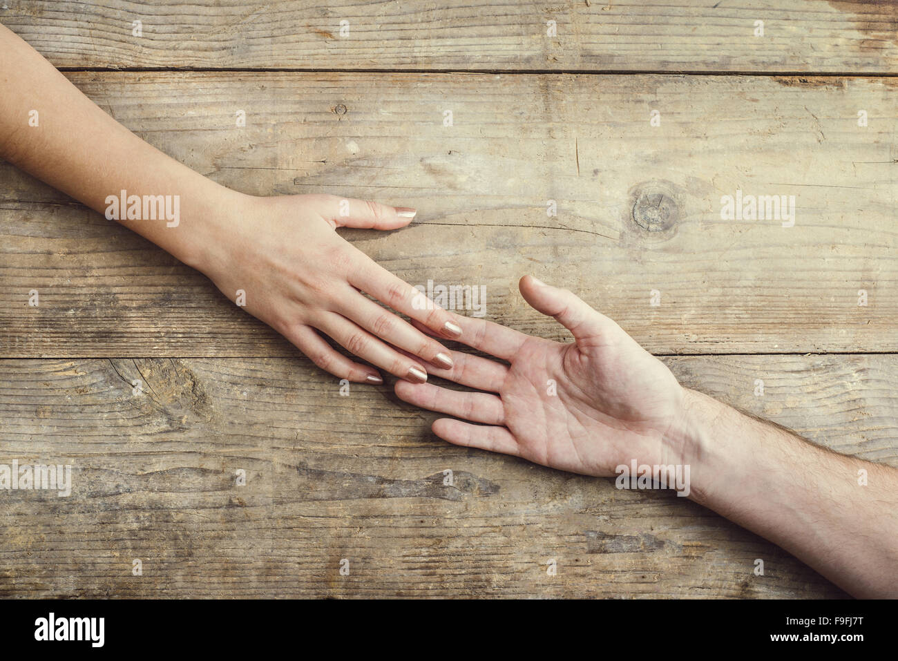 Hände von Mann und Frau zärtlich zusammenzuhalten. Studio auf einem hölzernen Hintergrund erschossen, Ansicht von oben. Stockfoto