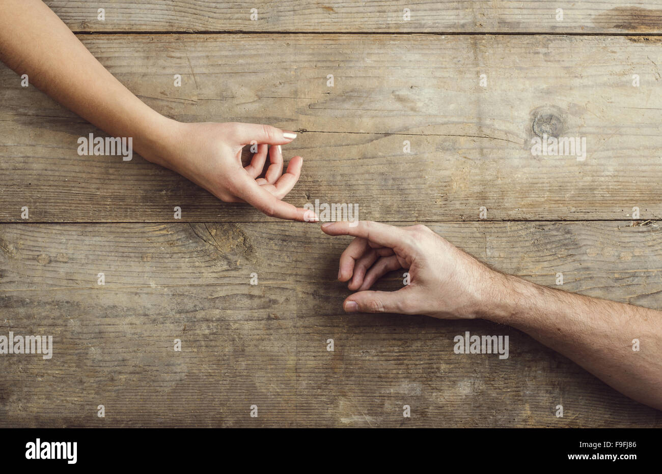 Hände von Mann und Frau zärtlich berühren. Studio auf einem hölzernen Hintergrund erschossen, Ansicht von oben. Stockfoto
