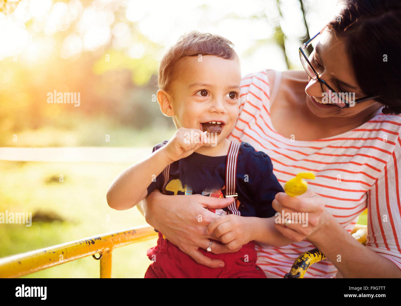 Glückliche junge Mutter mit ihrem Sohn auf einem Kinderspielplatz Stockfoto