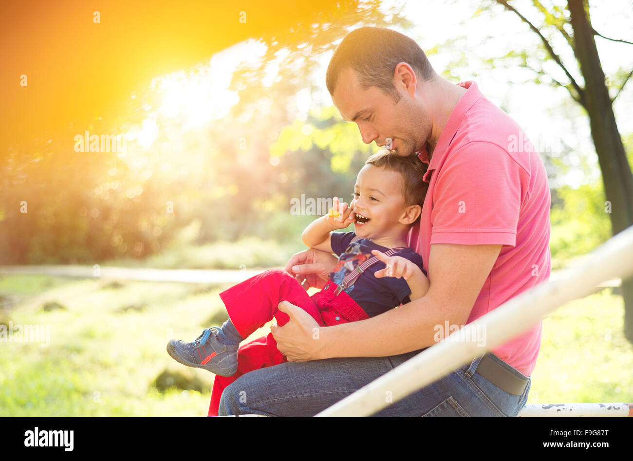 Glückliche junge Vater mit seinem Sohn auf einem Kinderspielplatz Stockfoto