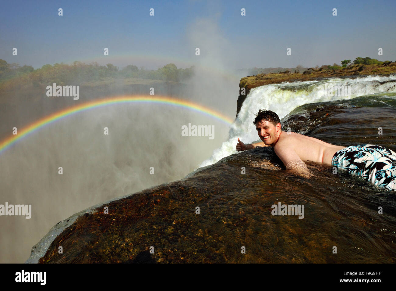 Lächelnd kaukasischen Mann Daumen aufgeben, am Rande der Victoriafälle in Teufels Pool, Sambia Stockfoto