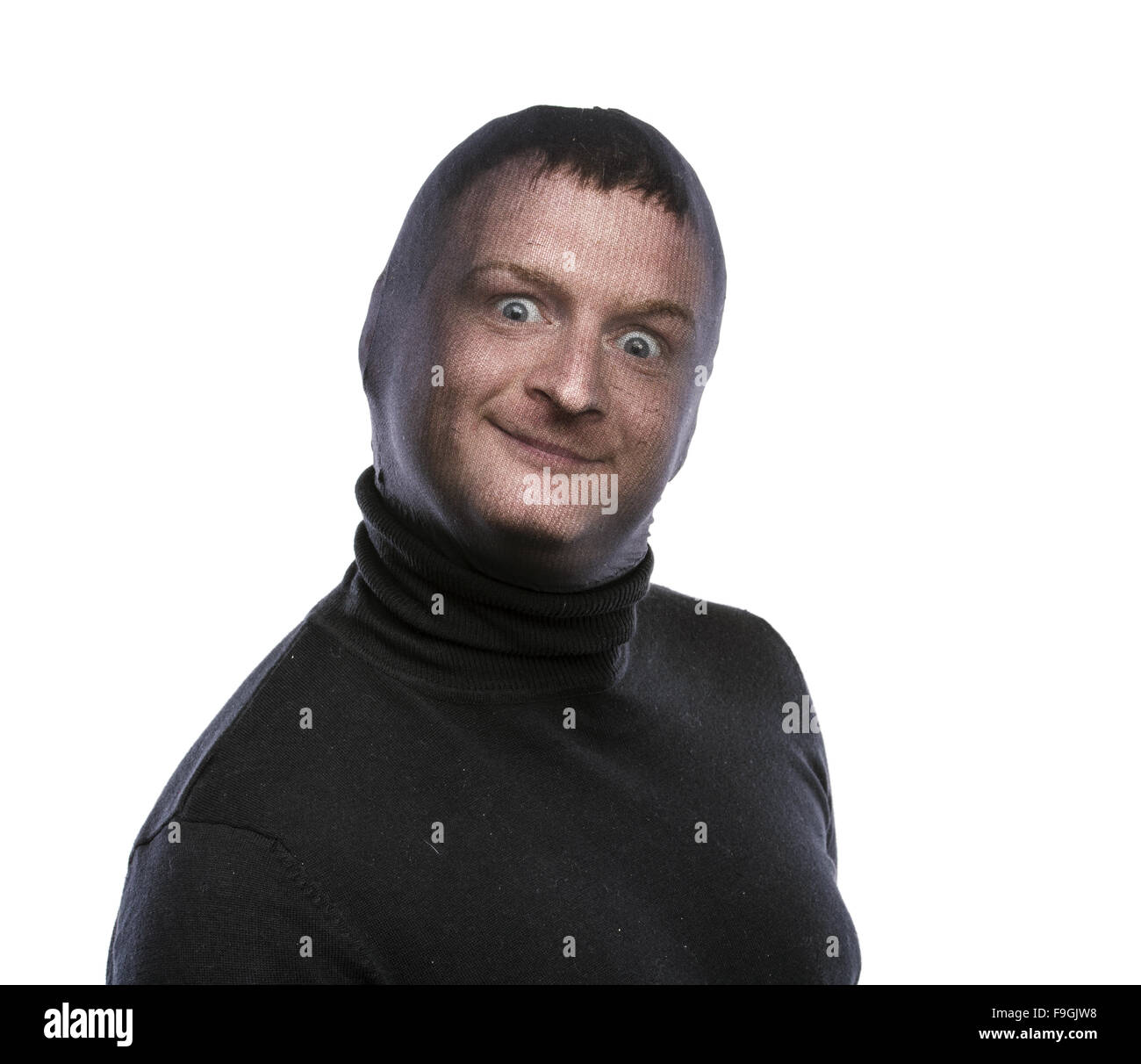 Dieb in Balaclava lustige Grimassen, in schwarz gekleidet. Studio auf weißem Hintergrund gedreht. Stockfoto