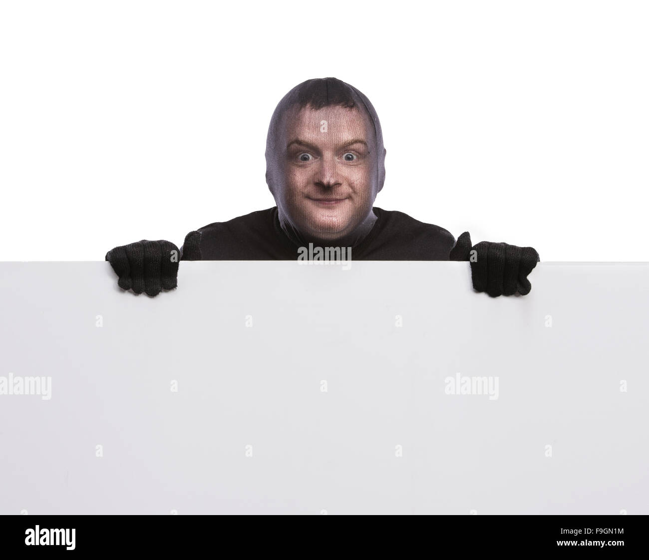 Dieb mit Sturmhaube auf seinem Gesicht, in schwarz gekleidet, hält einen leere Banner. Studio auf weißem Hintergrund gedreht. Stockfoto