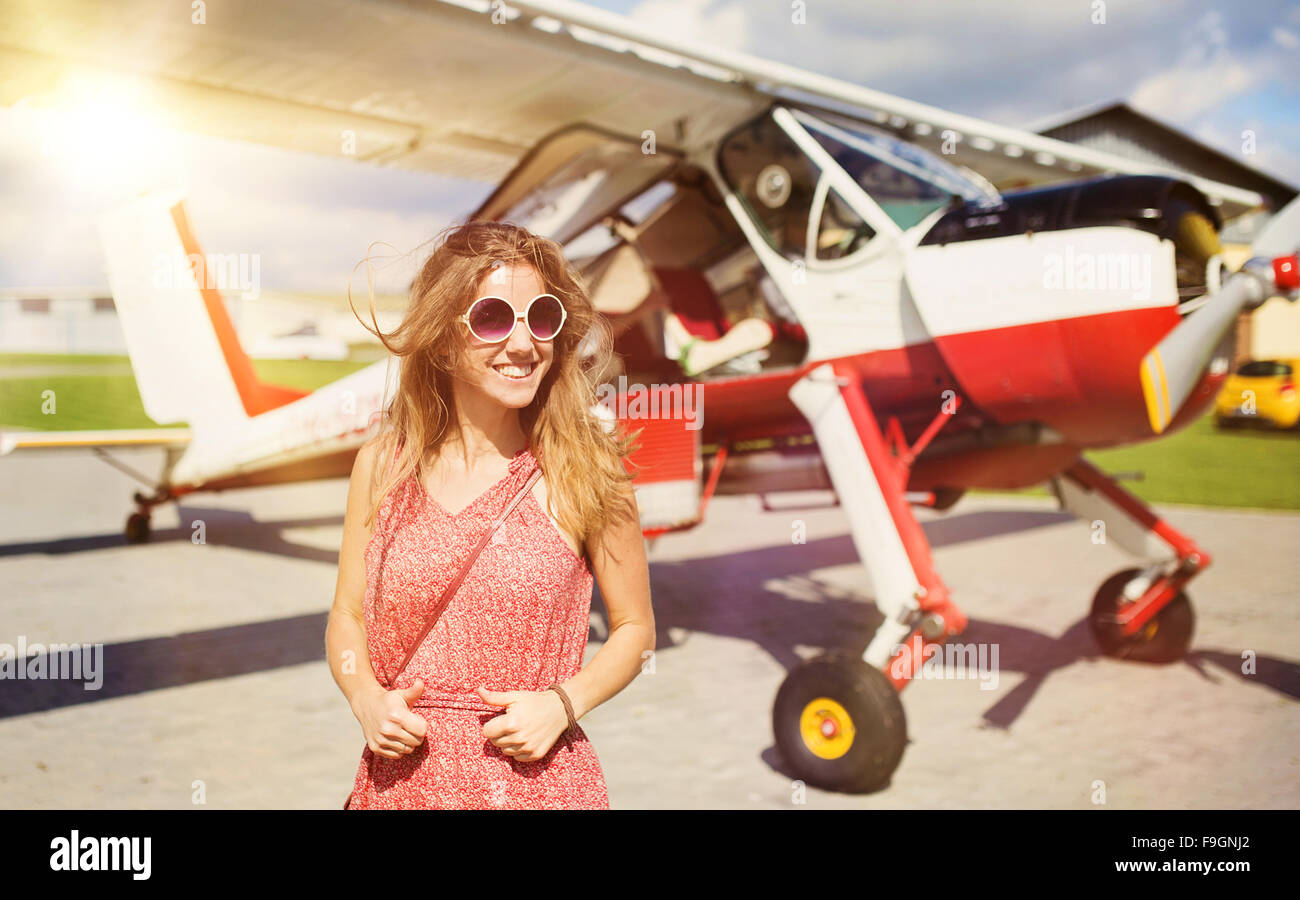 Schöne Frau im Sommer Kleid vor kleinen Oldtimer-Flugzeuge stehen. Stockfoto