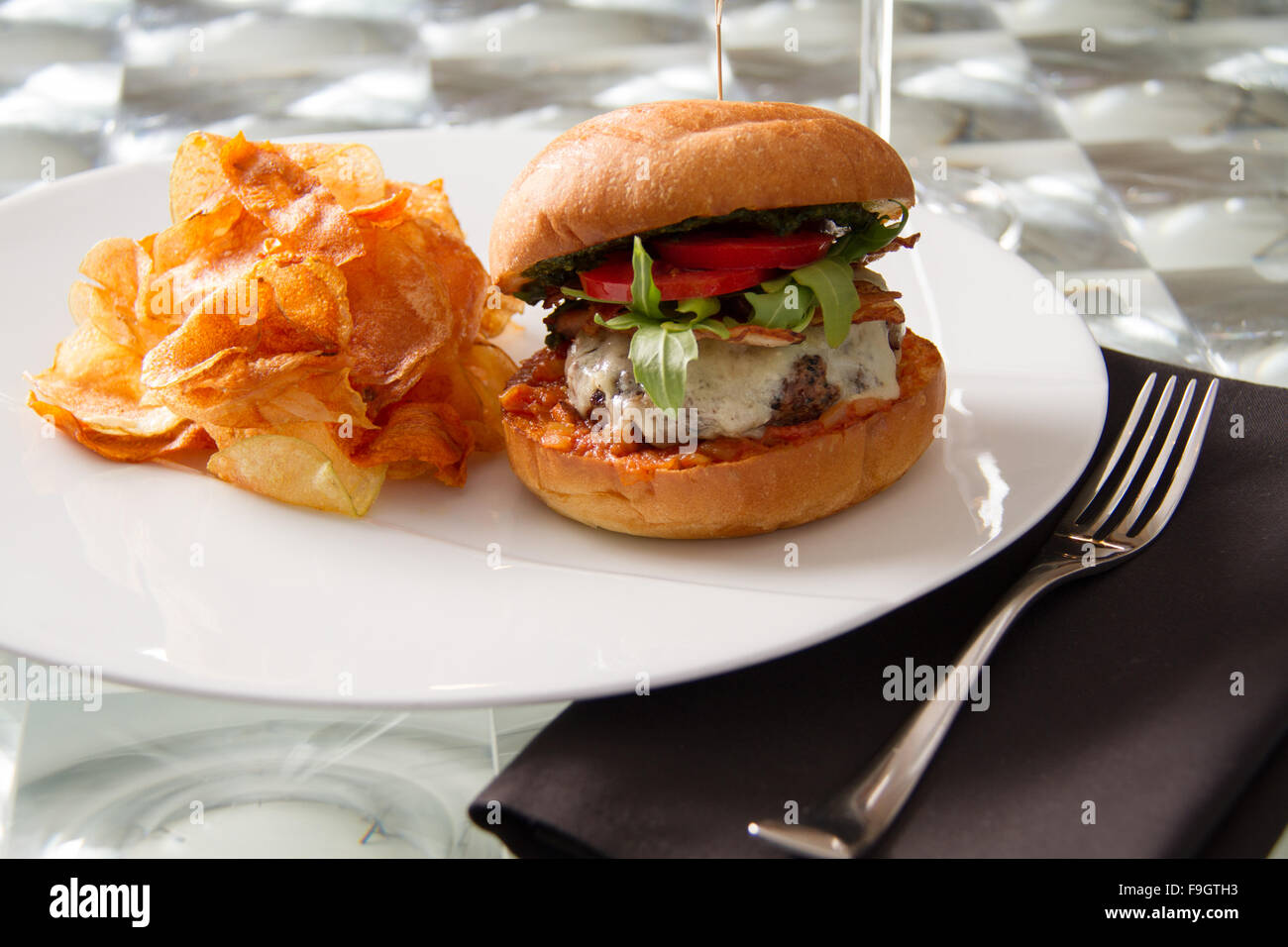Rindfleisch-Burger mit Alter Cheddar, karamellisierter Schweinebauch, Basilikum-Pesto, Rebe reife Tomate, Rucola auf einem Challah Brötchen mit Pommes frites Stockfoto